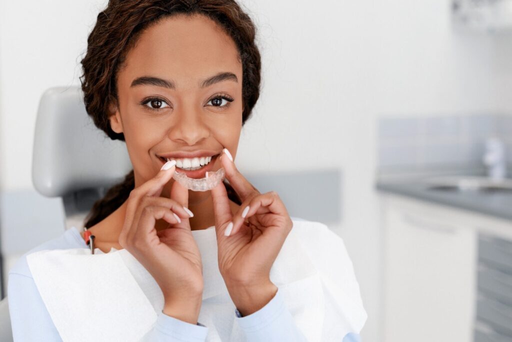 Jeune femme tenant une gouttière d'alignement transparente devant sa bouche